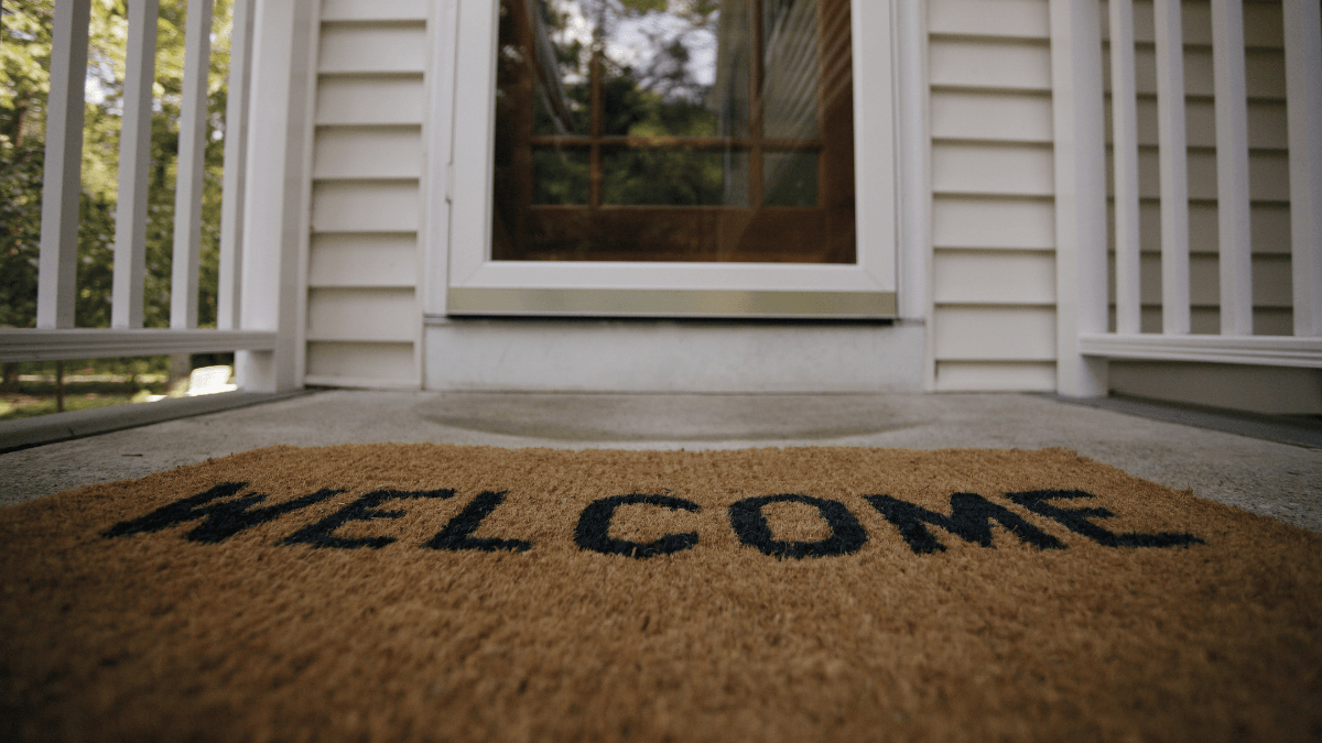 Pictured is a welcome mat in front of a house.