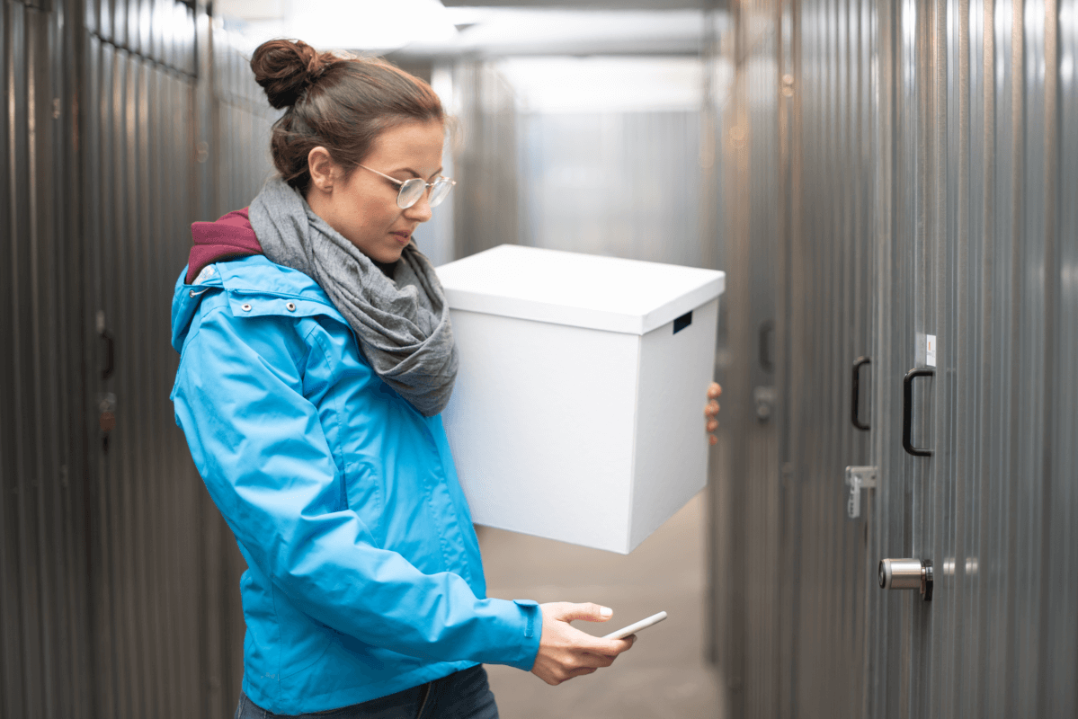 Frau öffnet Self Storage Bereich mit dem Smartphone