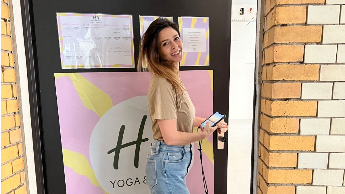 Woman unlocking the door of a yoga studio with smartphone